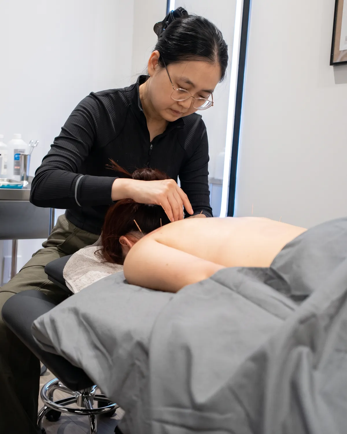 Registered acupuncturist placing fine needles during a treatment